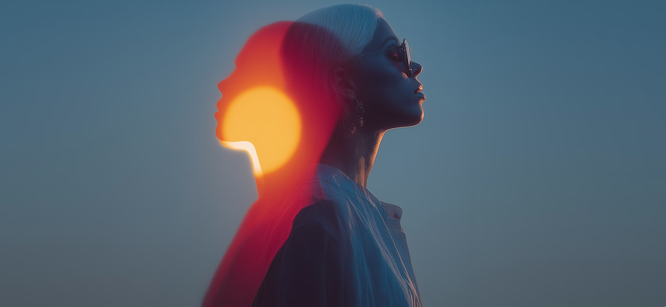 Double exposure portrait of a person in profile against a blue background, overlaid with a bright orange sun effect on their silhouette.